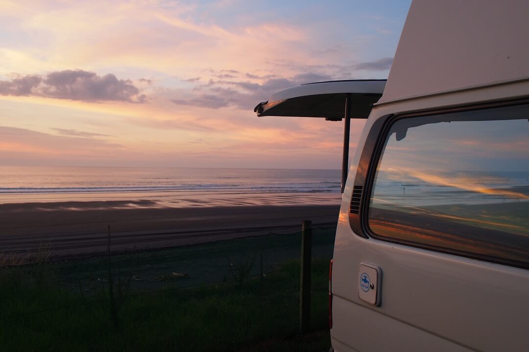 Camper parcheggiato vicino alla costa al tramonto in Nuova Zelanda