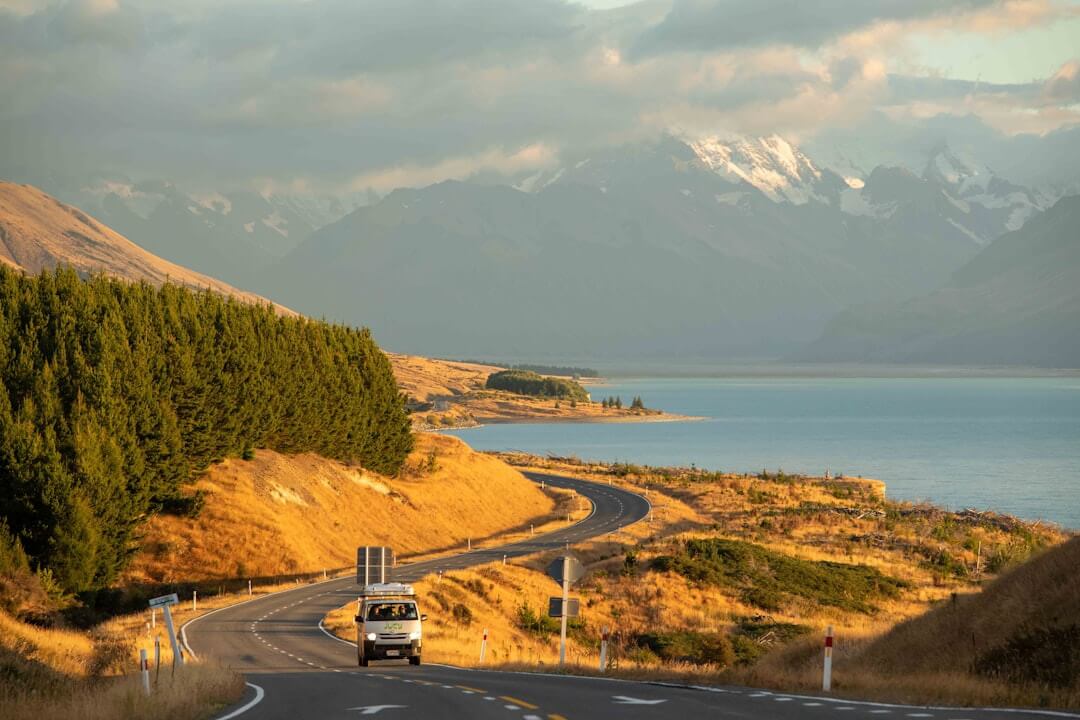 Veicolo in viaggio su una strada panoramica accanto a un lago in Nuova Zelanda